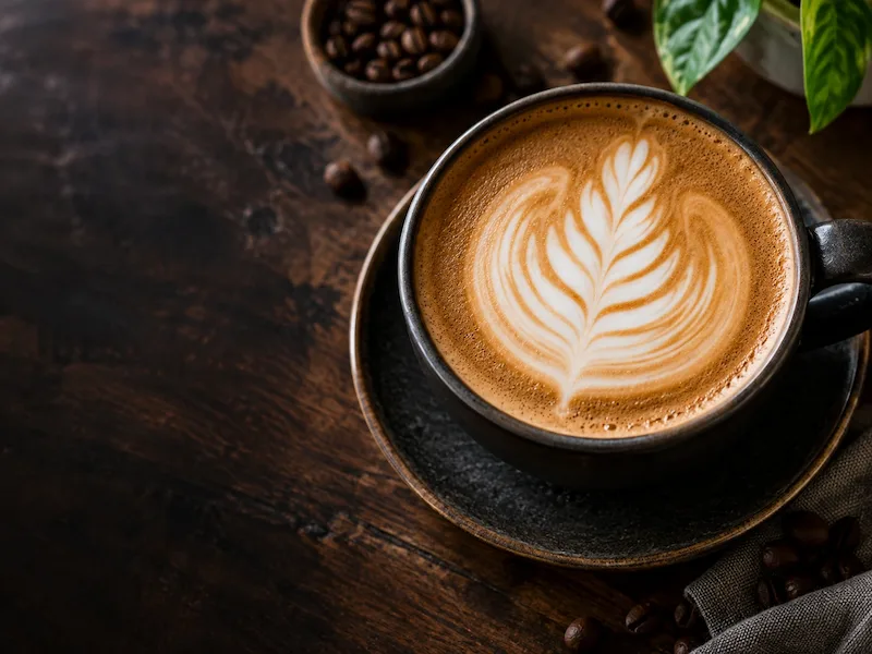 Latte with rosetta art on a warm wooden cafe table